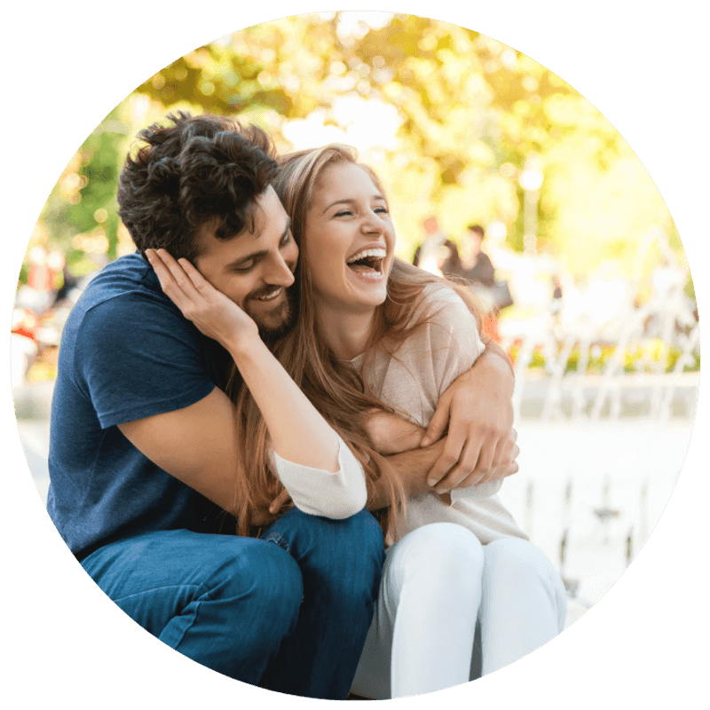 A couple laughing together outdoors, connected and at ease